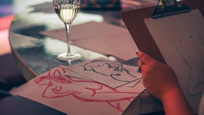 Colourful sketches on a table with a glass of wine