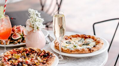 Glass of sparkling wine and pizza on a white topped table