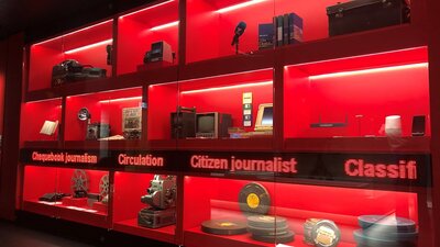 Red back-lit display of old publishing and broadcast technology items and scrolling ticker-tape sign