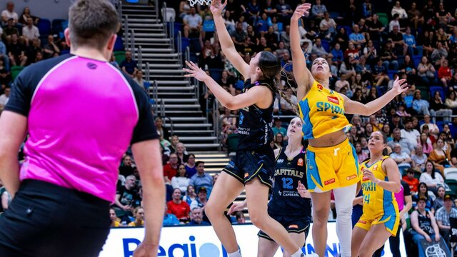 UC Capitals player driving to the basket for a layup during a WNBL game.