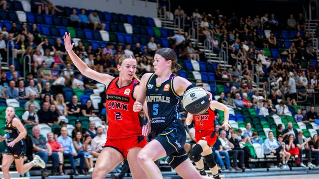 UC Capitals player driving to the basket for a layup during a WNBL game against Perth Lynx.