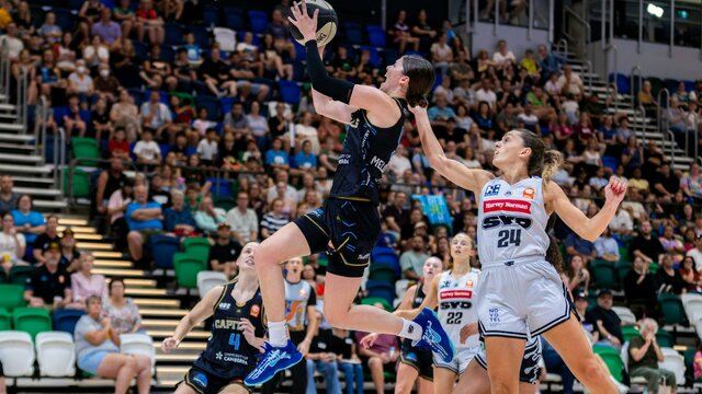 UC Capitals player driving to the basket for a layup during a WNBL game against Sydney Flames.