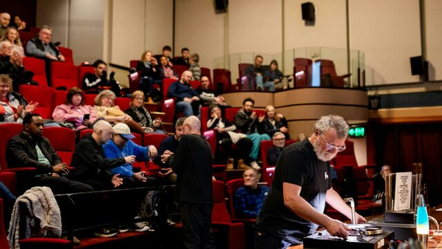 Vinyl Lounge Reconciliation Week 2025 Audience in a theatre and a man at the front preparing to play a vinyl