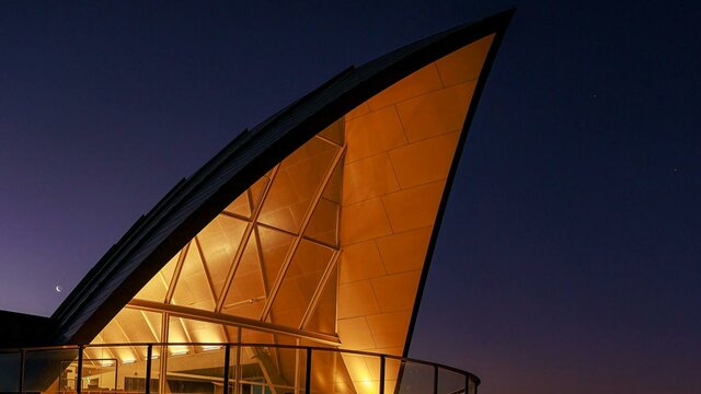 The triangular roof of the Margaret Whitlam Pavilion lights up against an evening sky