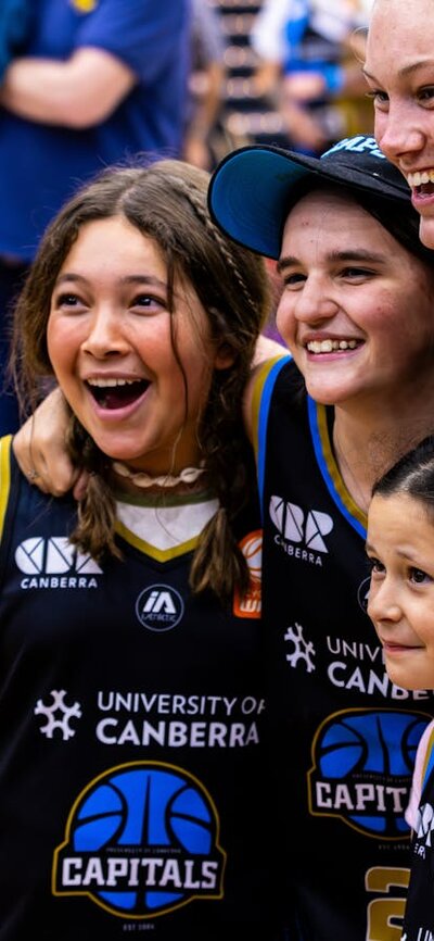 Nicole Munger of the UC Capitals poses with three young fans after a game