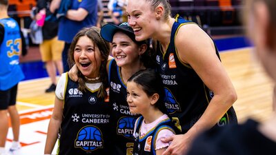 Nicole Munger of the UC Capitals poses with three young fans after a game