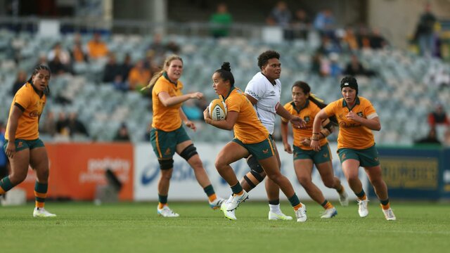 Rugby player running with ball in hand while team mates watch