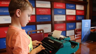 Boy concentrating while typing at a dark green typewriter