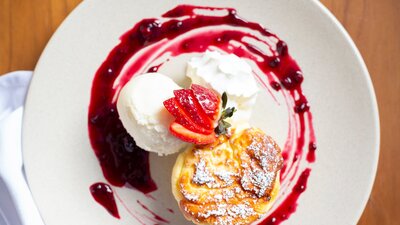A colourful dessrt of vanilla ice cream and raspberry jus on a white plate