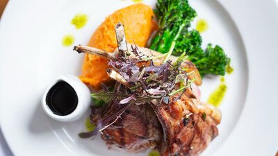 A colourful plate of meat and veggies on a white plate.