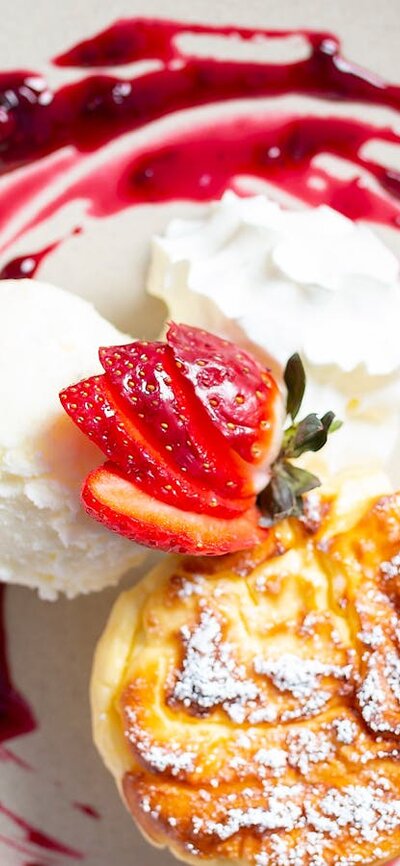 A colourful dessrt of vanilla ice cream and raspberry jus on a white plate