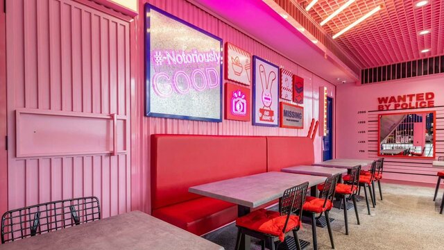Bright-pink interior decorated with various props. Red booths. (Bad Bunny's interior)
