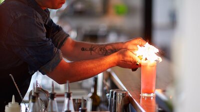 Barman lighting a cocktail on the bar