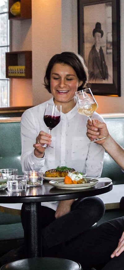 Couple with food and wine on tall stools by a fire place