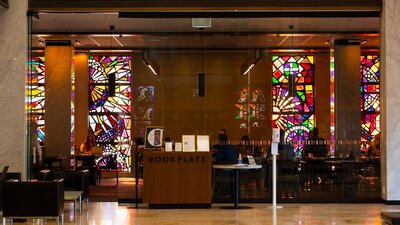 The front glass doors of a cafe. There are stained glass windows on the back wall of the cafe.