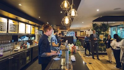 Wait staff serving drinks behind the bar with customers waiting to collect  drinks