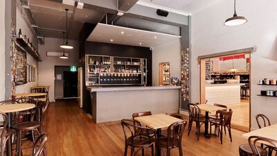 Wide view of room with bar, tables and chairs, no people