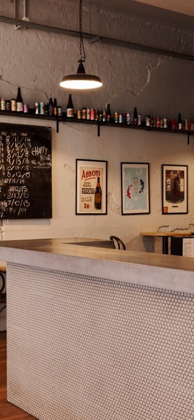 Bar with beer taps behind on the wall and bar tables against opposite wall