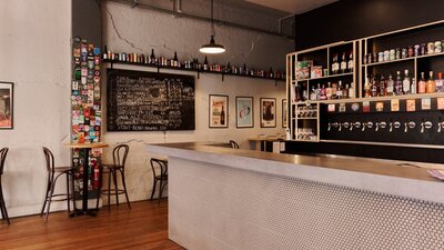 Bar with beer taps behind on the wall and bar tables against opposite wall