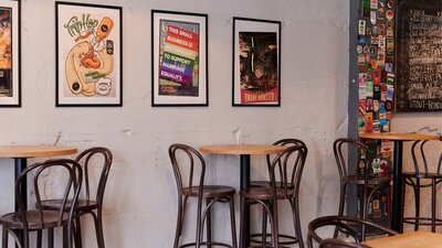 Bar tables against wall with posters in frames hanging on the wall