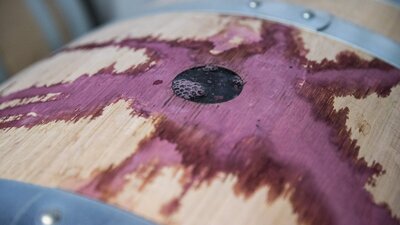 Red wine spills over the top of a French oak barrel.