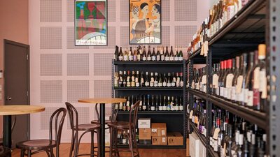 Tables and seating in front of wall shelf full of wines