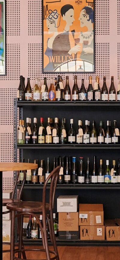 Tables and seating in front of wall shelf full of wines