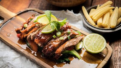 Roast duck on a plate with lime wedges