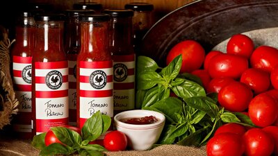 Jars of homemade relishes with fresh tomatoes and basil