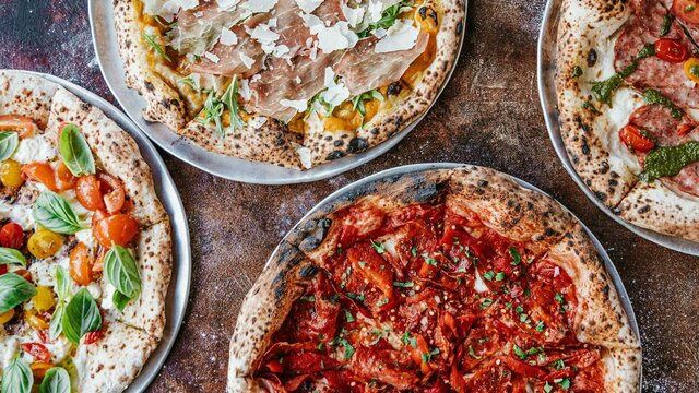 Four types of pizza laid out on a table