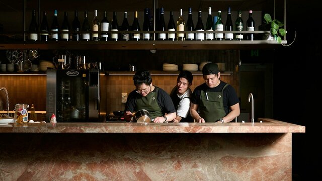 Sitting at the kitchen bar is the best way to experience the magic. Three chefs—one particularly good looking—preparing a meal behind a bench made of Italian marble