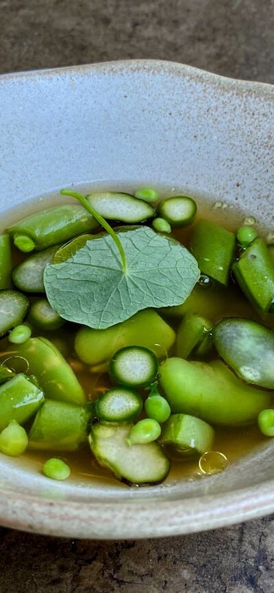 Broad beans, peas + nasturtium in a clear broth.