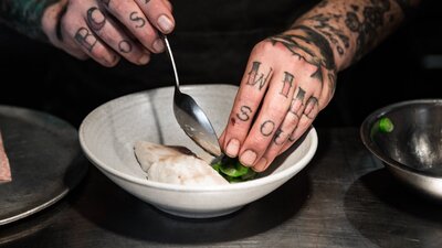 Head Chef Malcolm Hanslow plating a dish of steamed fish and greens.