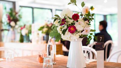 Beautiful white jug filled with fresh flowers on a wooden table