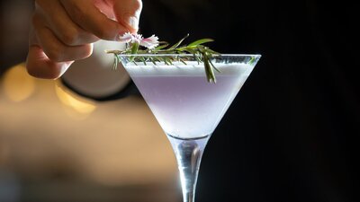 A bartender puts the finishing touches on a purple cocktail