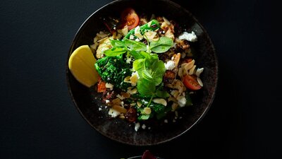 Three plates of colourful food set on a dark tablecloth