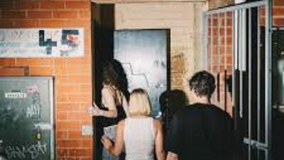 Group of people walking into doorway behind a brick wall