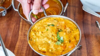 Hand lifting up a Korma curry