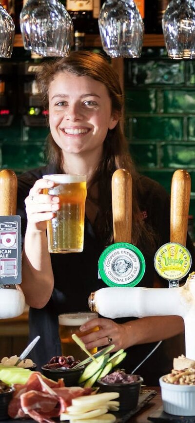 Bartender holding a pint of beer behind the bar