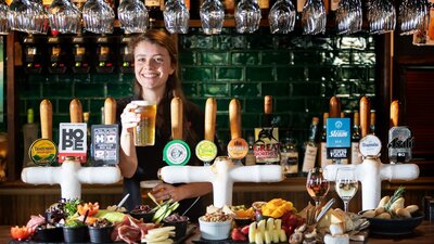 Bartender holding a pint of beer behind the bar