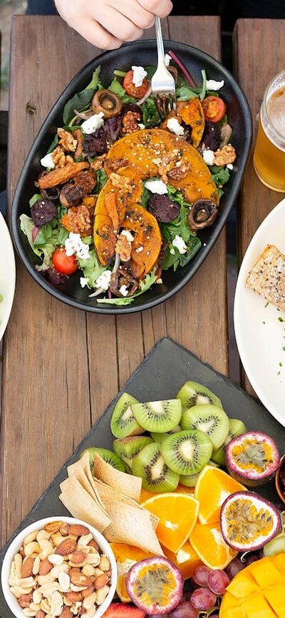 Three people eating  meals ontop of a wooden table