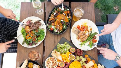 Three people eating  meals ontop of a wooden table