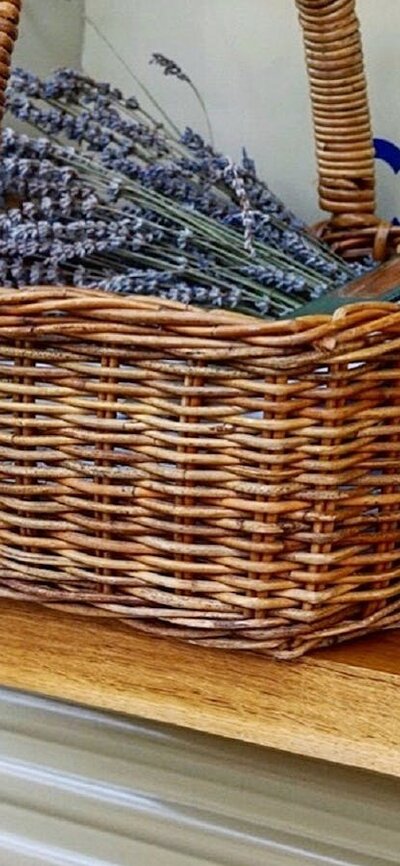 Wicker basket containing lavendar and a book next to a glass of sparkling wine