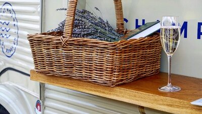 Wicker basket containing lavendar and a book next to a glass of sparkling wine