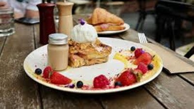 Plate lined with fruit, with pastries and jar of sauce set out on wooden table