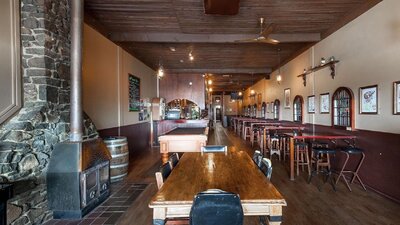 Pot belly woodfire on left-hand wall surrounded by stonework, with seating area and pool table throu