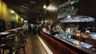 Tables and bar stools line the wall on the left, with a brightly lit bar with red tiles on the right