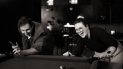 People laughing playing pool at bar