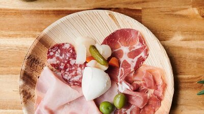 Antipasto platter on wooden table with bottle of wine