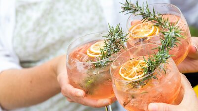 Three gin and tonics clink together to cheers